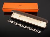 an orange box with a chain and a silver bracelet on a black surface