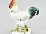 une figurine représentant un coq sur un socle blanc
