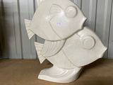 a white fish statue sitting on a table in front of a wall