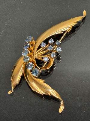 a gold brooch with blue stones on a black surface