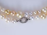 a close up of a white and yellow pearl necklace with a clasp