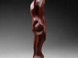 a wooden sculpture of a woman standing on a wooden base
