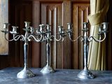 trois chandeliers en argent posés sur une table devant une fenêtre