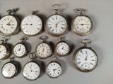 many different types of pocket watches displayed on a table
