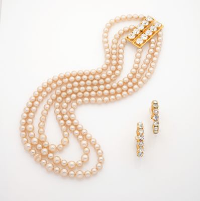 a close up of a necklace and earring with pearls on a white surface