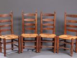 quatre chaises en bois sont alignées contre un mur gris