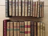 several old books are lined up on a shelf on a wooden table