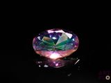 a close up of a colorful diamond on a black surface