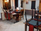 Il y a beaucoup de chaises et de tables dans cette pièce aux carreaux blancs.