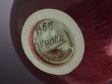 a close up of a red vase with a label on it