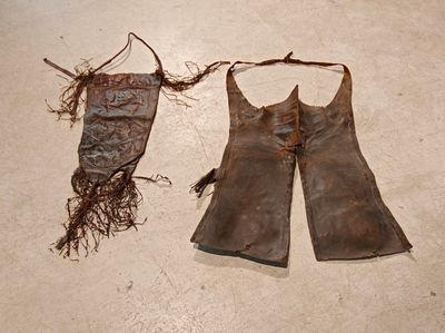 une paire de gants en cuir et un sac posé par terre