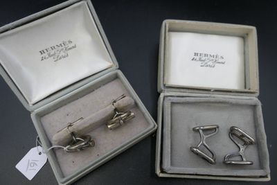 deux paires de boutons de manchette en argent dans un écrin posé sur un fond noir