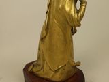 gold statue of a woman holding a baby on a wooden base