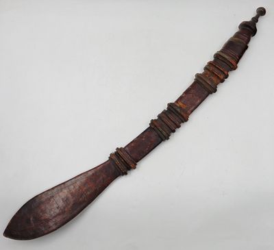 un vieux couteau en bois à longue lame posé sur une surface blanche