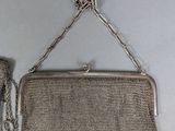 an antique silver mesh purse with a chain hanging from it ' s side