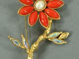 broche en forme de fleur dorée et rouge, ornée de perles et de feuilles