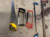 des outils posés par terre à côté d'une table, parmi lesquels un marteau, une scie et d'autres outils