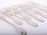 six silver spoons are arranged in a row on a white surface