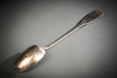 une cuillère en argent avec un manche de cuillère sur une surface grise
