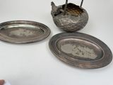 a silver plate with a bird on it next to a silver plate with a bird on it