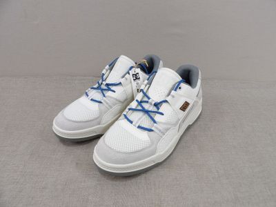 des baskets blanches avec des lacets bleus, posées sur une surface grise