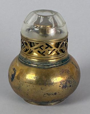 a small gold vase with a glass top on a table