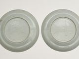 pair of chinese celade plates with raised rims on a white background