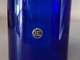 a blue glass vase with a silver logo on it