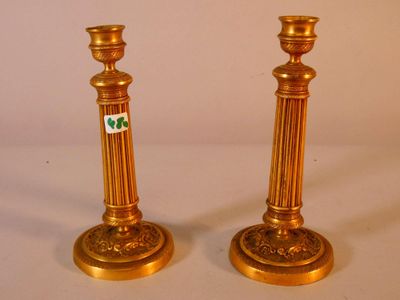 pair of antique brass candlesticks with green and white stickers