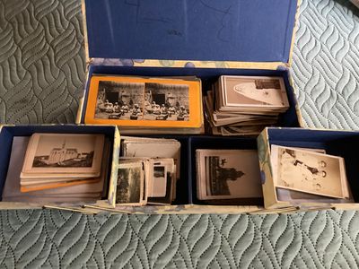 a blue box filled with old photos on a bed