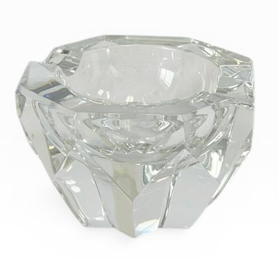 un bougeoir en verre transparent posé sur une surface blanche