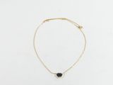 un collier en or orné d'une pierre noire sur fond blanc