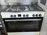 une cuisinière dans une petite cuisine, avec une casserole posée dessus