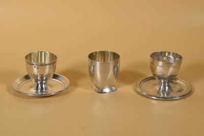trois tasses et soucoupes en argent sont posées sur une table
