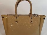 un sac à main beige muni d'une poignée en métal et d'une fermeture à glissière