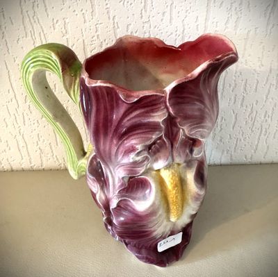 un vase violet muni d'une anse verte, posé sur une table