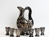 a pitcher and four cups sitting next to each other