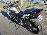 a white and black motorcycle parked in front of a fence
