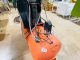 an orange air compressor sitting on top of a wooden floor