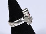 an image of a silver ring with a red stone in it