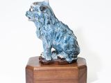 statue of a dog sitting on a wooden base on a white background