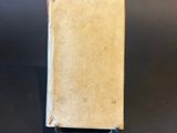 an old book sitting on top of a table on a black surface