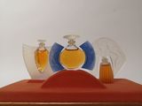 three perfume bottles sitting on top of a red box