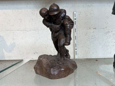 une statue représentant un footballeur tenant un ballon, posée sur une table en verre