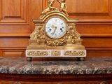 a clock on top of a marble table in front of a painting