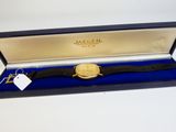 une photo d'une montre dans un coffret, avec une étiquette dessus