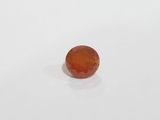 an orange jade stone on a white surface