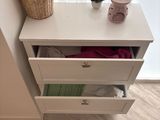 a small white chest of drawers next to a window