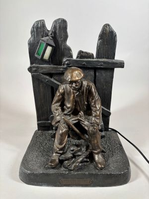 bronze statue of a man sitting on a bench with a computer