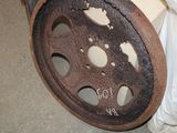 a rusted wheel with holes on it sitting on the floor